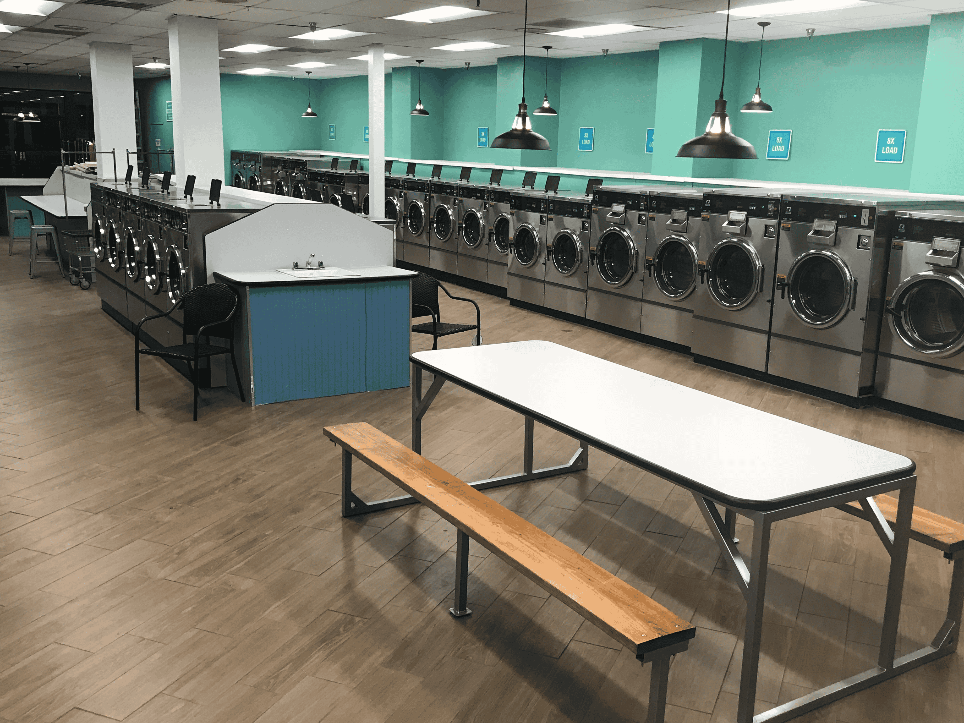 Spacious laundromat with rows of washing machines and benches